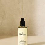 Aesthetic product shot of Blossera Belly Oil with oil dripping to show lightweight, nourishing texture.